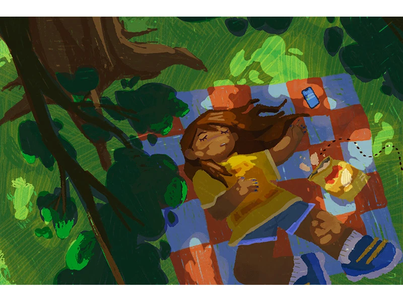 Child lying on a checkered picnic blanket under trees with dappled light, surrounded by a bag of chips and a can.