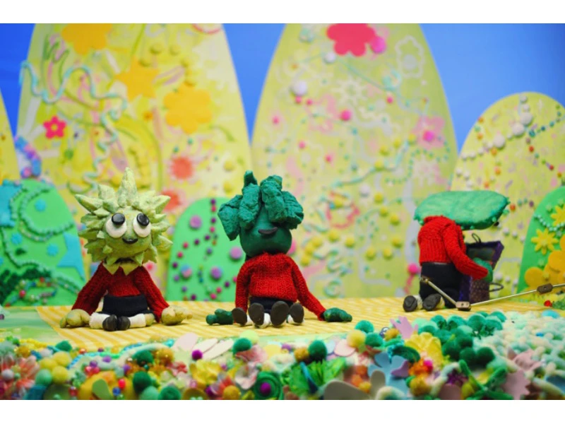 Whimsical clay figures with plant heads against a colorful, abstract background with cone-shaped hills.