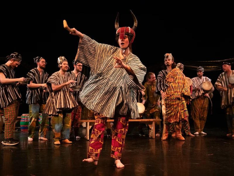 Performance of people in traditional African attire with instruments on stage.