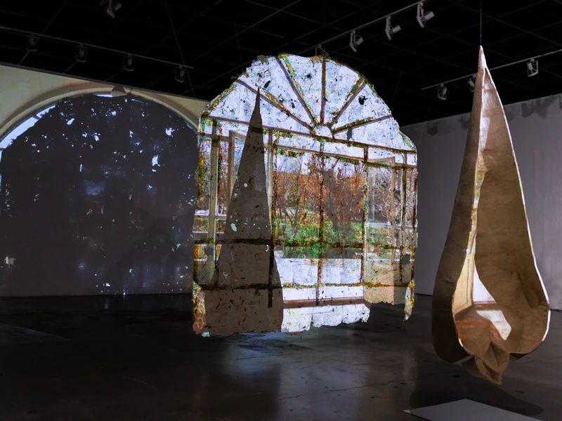 Abstract art installation with projected images on suspended structures in a gallery.