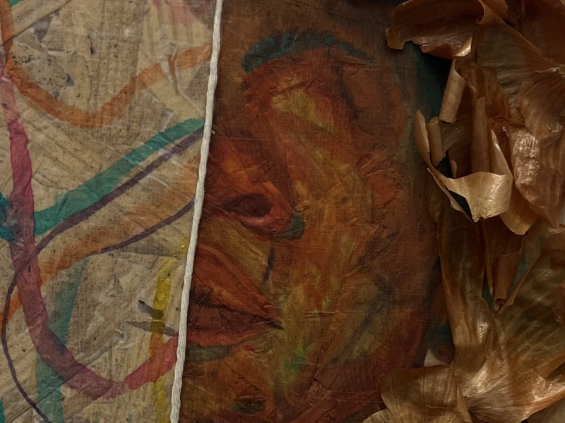 Close-up of a mixed-media artwork with colorful swirls and an abstract face.