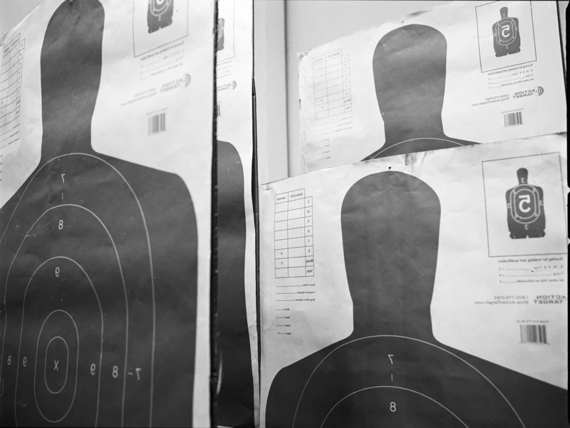 Black and white image of shooting target sheets with concentric circles and silhouette figures.
