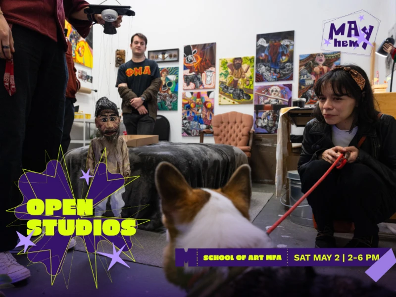 A lively art studio scene with a marionette, dog, and people interacting near colorful paintings.
