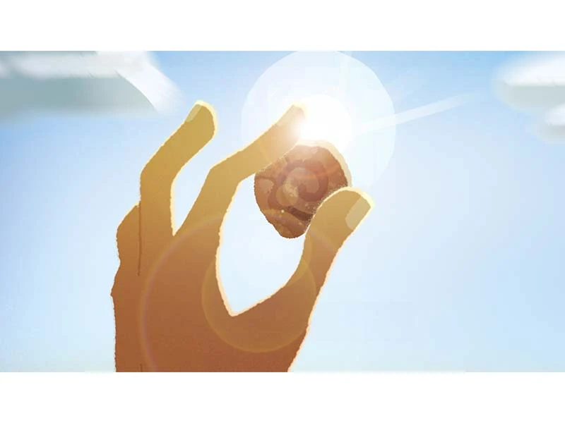 Hand holding a small object up to the sunny sky with lens flare effects.