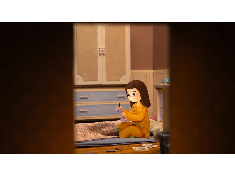 A young girl in a yellow sweater sits on a rug in a cozy room, engaged in an art project. The scene is viewed through a doorway, revealing parts of wooden furniture and art supplies around her.