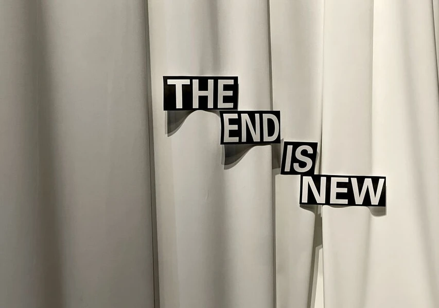 Text "THE END IS NEW" on white curtains.