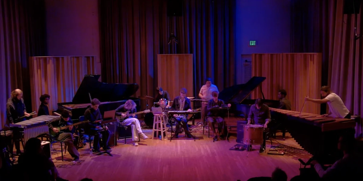 Musicians performing with various instruments on a dimly lit stage.