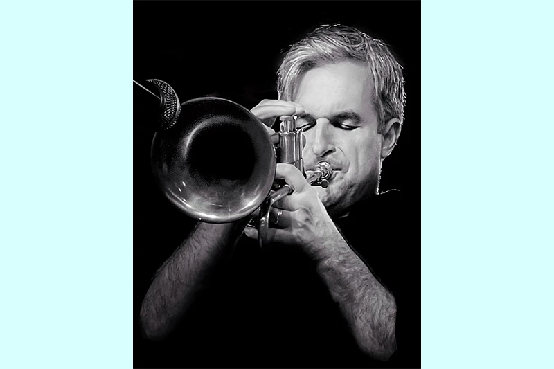 Musician playing a trumpet in a black and white photograph.