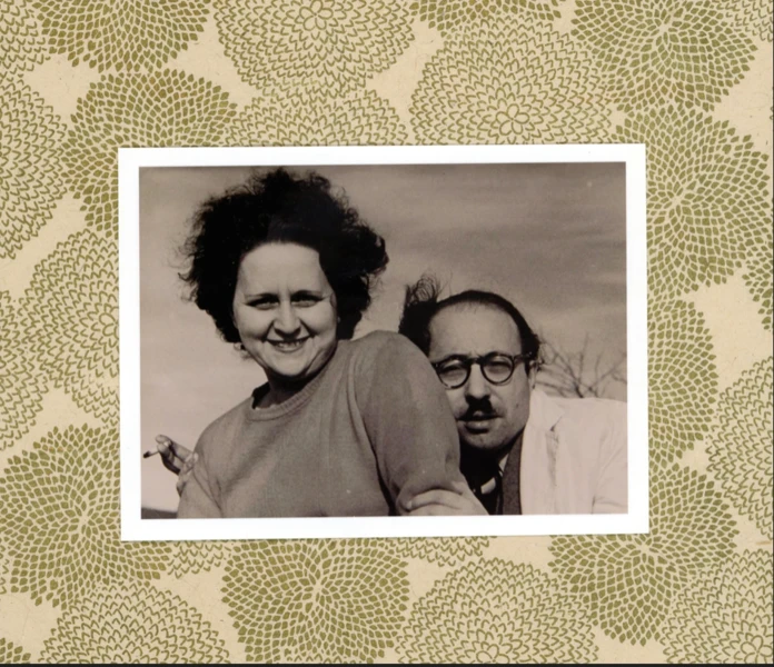 Black and white photo of a smiling woman with a man behind her, framed by a floral patterned border.