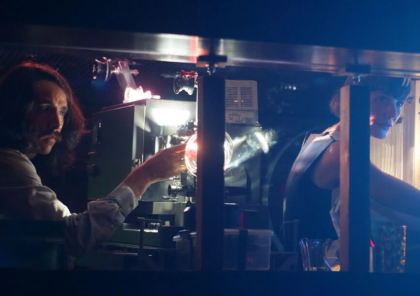 Two people operating projection equipment in a dimly lit room.