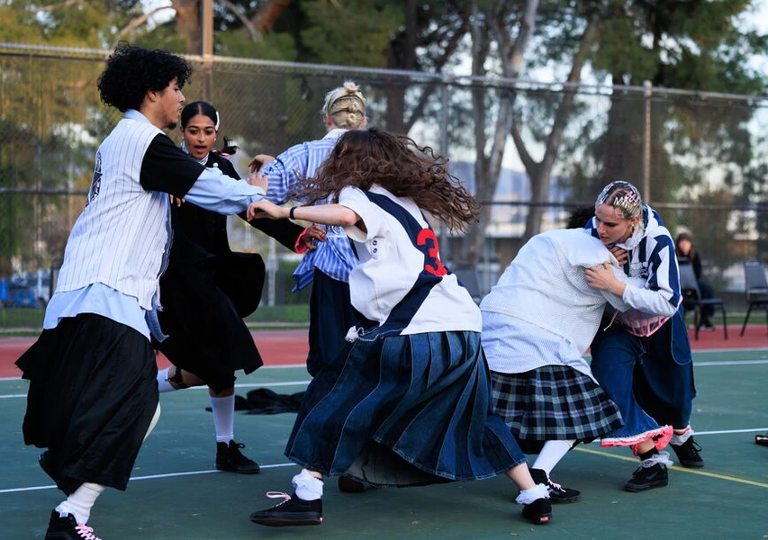 Group of people playing on an outdoor basketball court, wearing casual and sports apparel