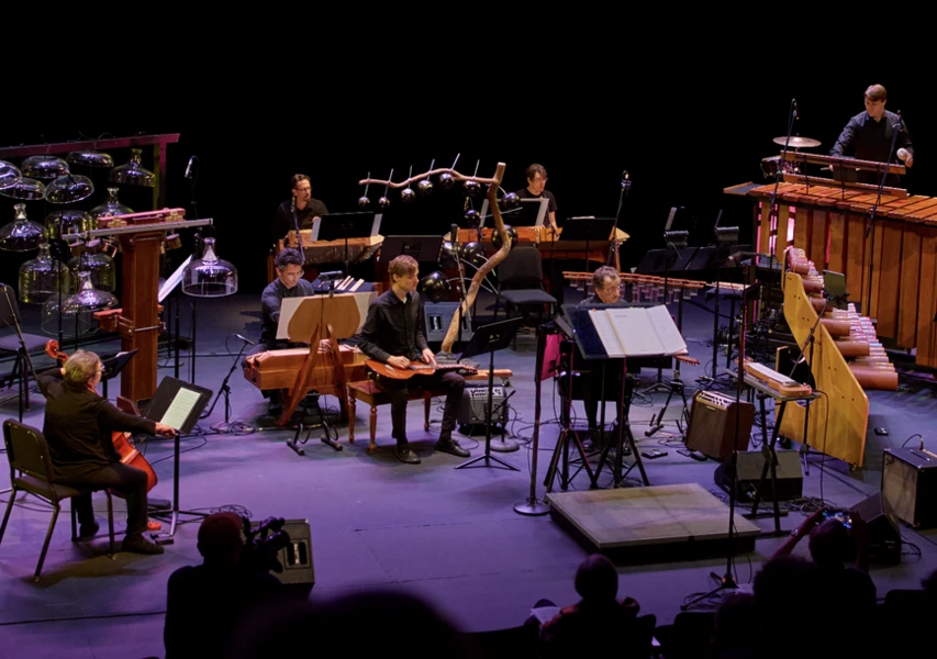 Musicians perform on stage with unusual and diverse instruments.