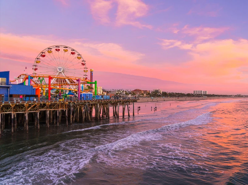 Santa Monica Pier with Ferris wheel at sunset with pink, orange, and purple sky.